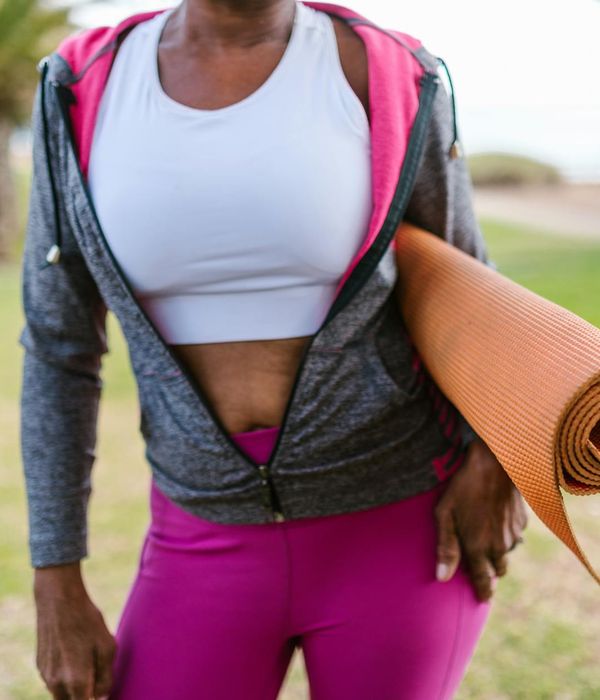Woman smiling and stretching outdoors in a park.